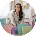 Mujer sonriente sentada en el suelo rodeada de bolsas de compra, simbolizando la satisfacción y alegría por las compras de Fajas Salome.